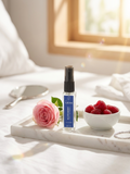 Skincare serum bottle on a marble tray with a rose and raspberries, soft natural light.